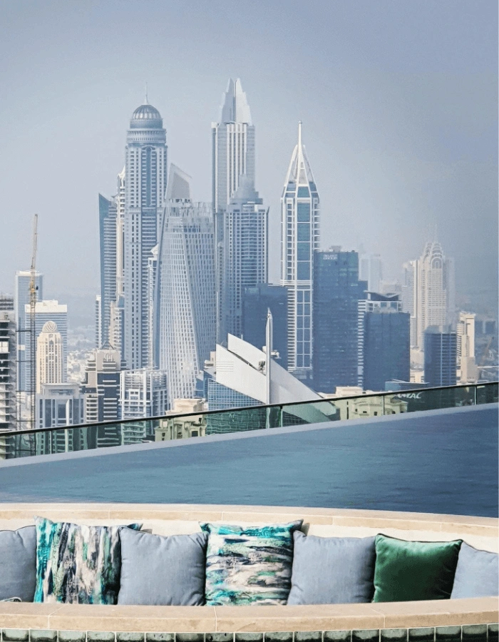 בריכת אינפיניטי יוקרתית עם פינת ישיבה צבעונית ונוף עוצר נשימה לגורדי השחקים של דובאי ביום בהיר